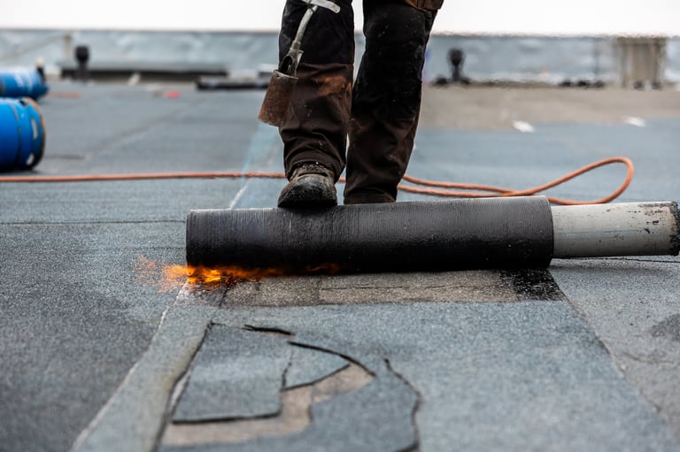 professional roofer at work securing rolled material on a flat roof