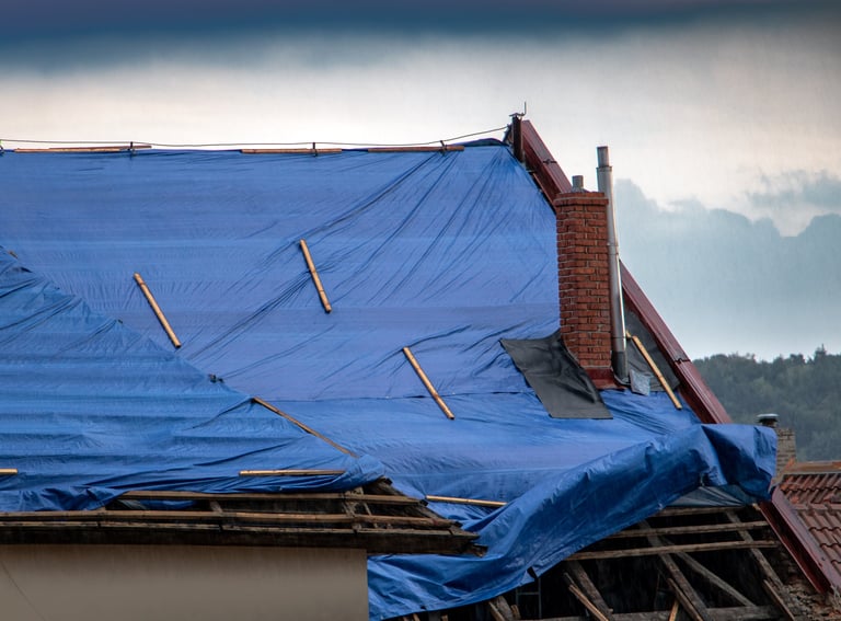 The protective tarpaulin on the roof flutters at the storm with rain