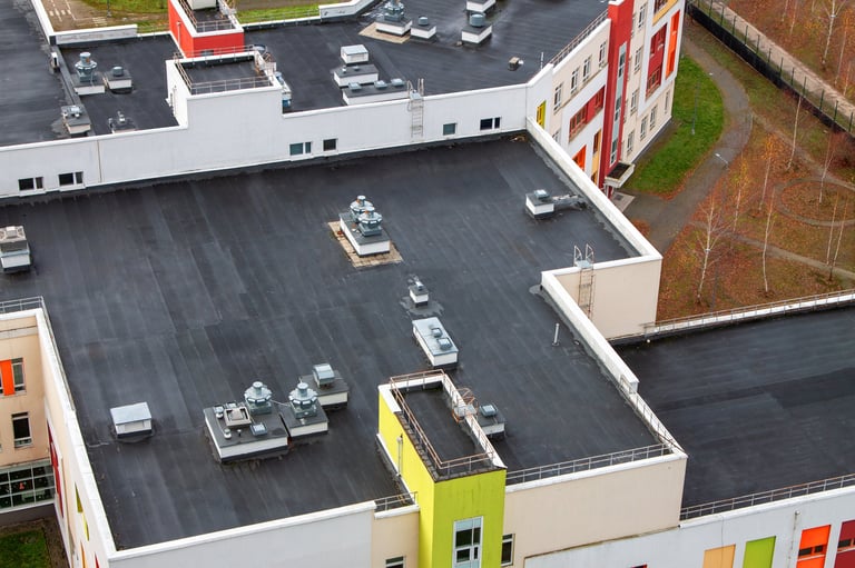 Flat rooftop with multiple ventilation systems and technical equipment on a modern multistory building