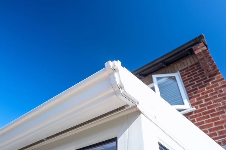 Close-up of white plastic guttering seen on a conservatory which extends from the main house