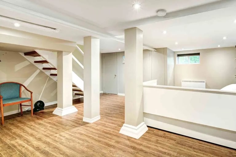 Modern basement reception area with white columns, wood flooring, staircase, and minimalist desk counter