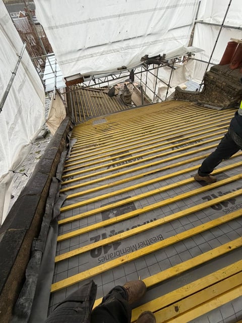 Construction site with yellow steel floor beams and metal railings under white protective sheeting